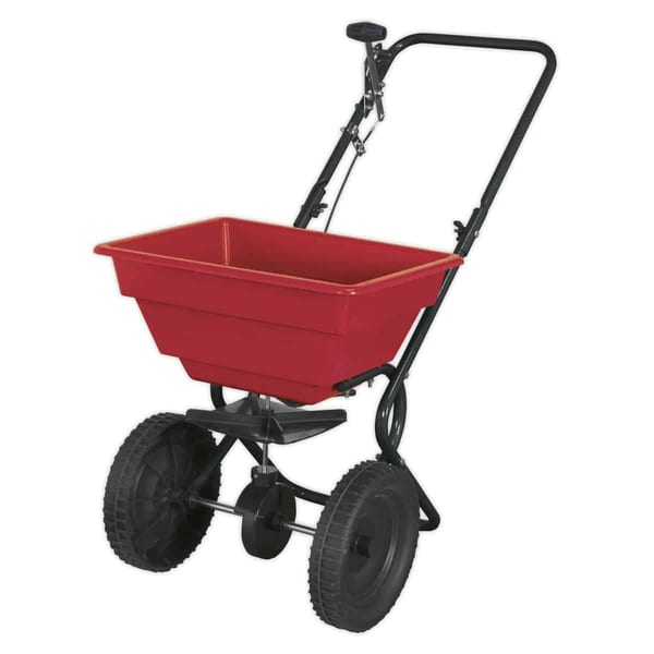 Red garden spreader with large wheels for easy movement, ideal for spreading seeds, fertiliser, or other materials in gardens.