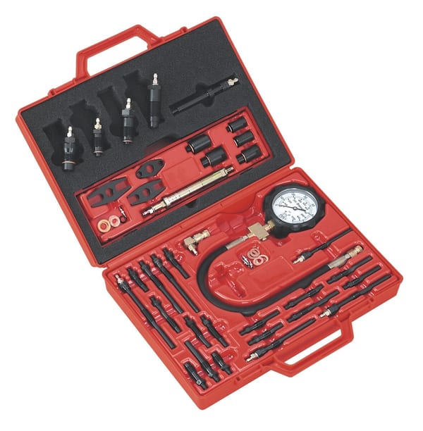 Diesel engine compression test kit with gauge and various adapters in a red case.