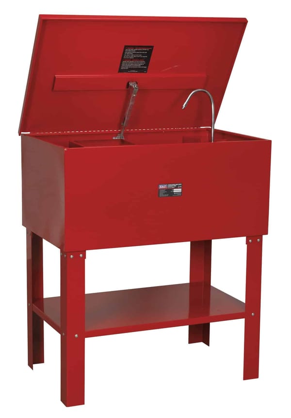 Red parts washer with a hinged lid and a sink, featuring a sturdy stand and a lower shelf for storage.